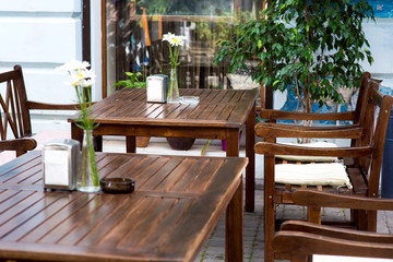 outdoor cafe with free tables for relaxing in the open air near the facade of the building with a window and flowerpots with plants.