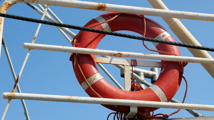 Red lifebuoy attached to a ship railing