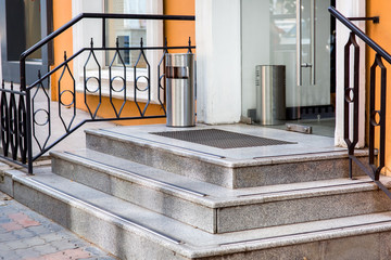 entrance to the store with stone steps and a glass door, at the entrance a rubber foot pad and an iron urn. © Александр Беспалый