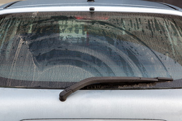 dirty car rear window gray wagon covered with dust wet after rain.