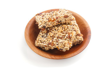 Homemade granola from oat flakes, dates, dried apricots, raisins, nuts in brown wooden plate isolated on white background. side view.