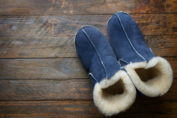 Handmade warm house shoes from sheepskin and sheep fur on weathered wood background. Winter autumn...