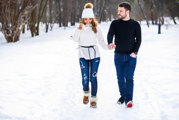 Loving couple walking on a date in a winter Park. On the girl's back hanging a pair of skates.