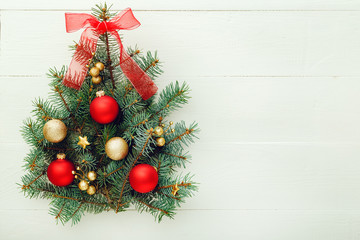 Fototapeta na wymiar Xmas New Year pattern composition: Christmas Tree made from fir branches, red, gold balls on white wooden background, concept of holiday celebration 2020. Flat lay, top view, copy space.