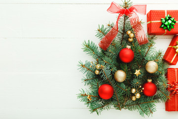 Xmas New Year pattern composition: Christmas Tree made from fir branches, red gift boxes on white wooden background, concept of holiday celebration 2020. Flat lay, top view, copy space.