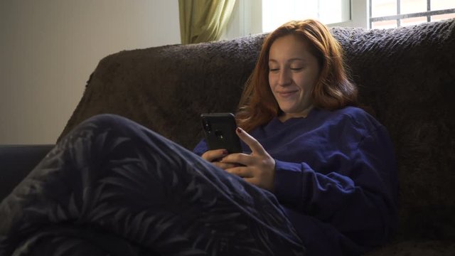 Young successful woman using smartphone app at home. Excited girl receiving good news