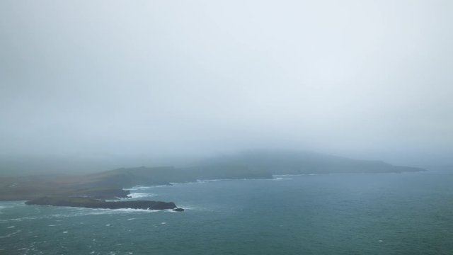 footage of bray head on the ring of kerry in the south coast of ireland on a stormy day showing battering waves and green grass on rocky coastline