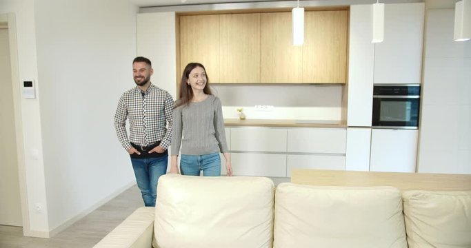 Cheerful husband and wife looking around in new apartment, feeling happy and hugging, investment