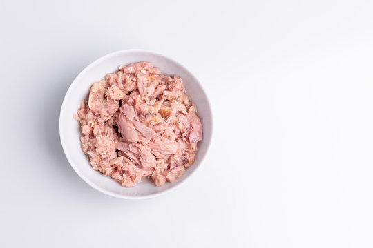 Canned tuna in a white bowl, isolated on white background; copy space, soft light, studio shot