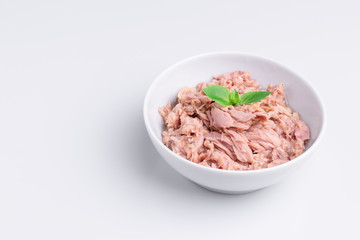Canned tuna in a white bowl, isolated on white background; copy space, soft light, studio shot