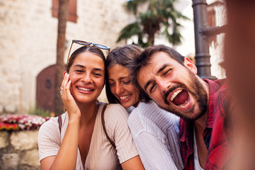 Obraz premium Smiling friends make looking at camera and make selfie