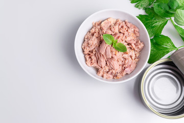 Canned tuna in a white bowl, isolated on white; empty open tuna tin on a white background; copy space, soft light, studio shot