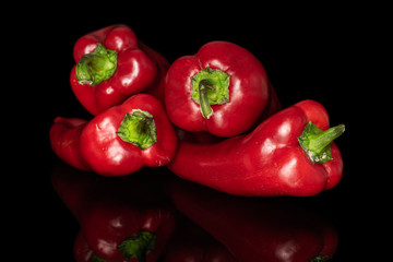Group of four whole sweet red bell pepper isolated on black glass