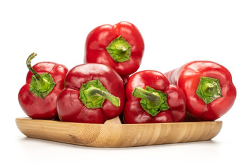 Group of five whole sweet red bell pepper on wooden square plate isolated on white background