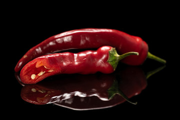 Group of one whole one half of fresh hot pepper isolated on black glass