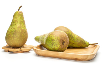 Group of three whole fresh green pear conference on wooden square plate on tree stump isolated on white background