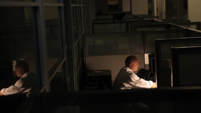 Satisfied and happy mature businessman typing on computer keyboard working late at the office
