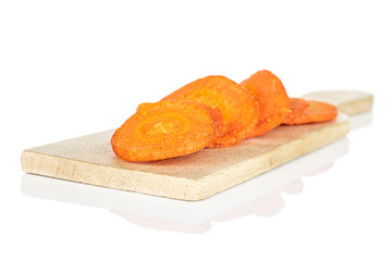 Group of four whole dry vegetable chip of carrot on small wooden cutting board isolated on white background