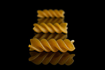 Group of three whole dry brown wholegrain fusilli isolated on black glass