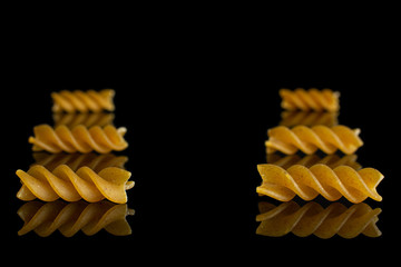 Group of six whole dry brown wholegrain fusilli isolated on black glass