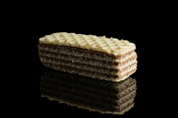One whole crispy beige hazelnut wafer cookie isolated on black glass