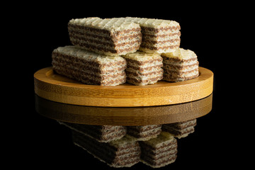 Group of five whole crispy beige hazelnut wafer cookie on bamboo coaster isolated on black glass