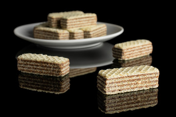Lot of whole crispy beige hazelnut wafer cookie on white ceramic plate isolated on black glass