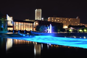 Panoramic view of downtown South Bend Indiana at night with the St Joseph river in the foreground, Century Center in the background and the St Joseph river lights on.