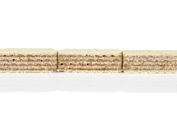 Group of three whole crispy beige hazelnut wafer cookie in row isolated on white background