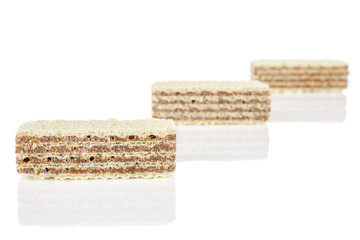 Group of three whole crispy beige hazelnut wafer cookie placed diagonally isolated on white background