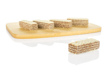 Group of five whole crispy beige hazelnut wafer cookie on bamboo cutting board isolated on white background
