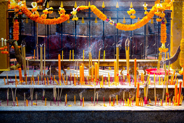 Incense and burning candles at the Erawan Shrine in Bangkok, Thailand