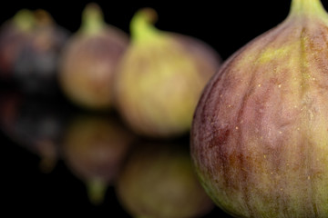 Group of four whole sweet purple fig isolated on black glass