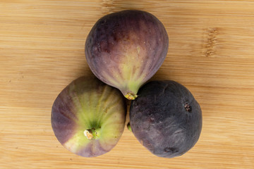 Group of three whole sweet purple fig flatlay on light wood