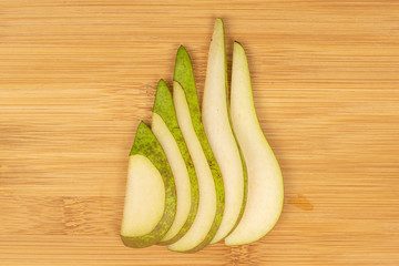 Group of five slices of fresh green pear flatlay on light wood
