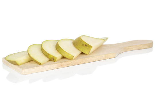 Group of five slices of fresh green pear on wooden cutting board isolated on white background