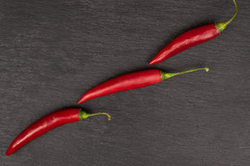 Group of three whole hot red chili cayenne flatlay on grey stone