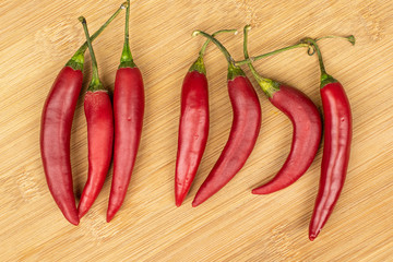 Group of seven whole hot red chili cayenne flatlay on light wood