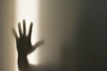 Shadow of hand showing stop sign on the wall, halloween concept.