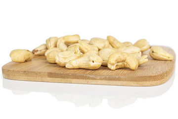 Lot of whole brown nut cashew on bamboo cutting board isolated on white background