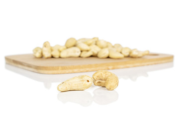Lot of whole brown nut cashew on bamboo cutting board isolated on white background