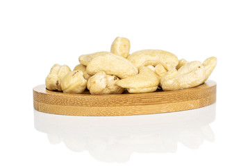 Lot of whole brown nut cashew on round bamboo coaster isolated on white background