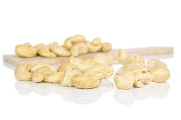 Lot of whole brown nut cashew on wooden cutting board isolated on white background