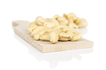 Lot of whole brown nut cashew heap on wooden cutting board isolated on white background