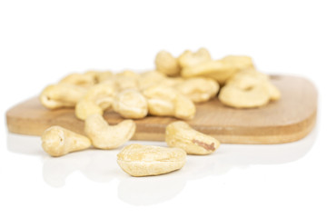 Lot of whole brown nut cashew on bamboo cutting board isolated on white background