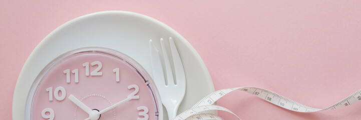 Pink clock on white plate, Intermittent fasting concept, ketogenic diet, weight loss, skip meal