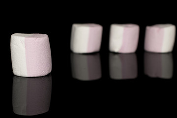 Group of four whole sweet pastel marshmallow isolated on black glass