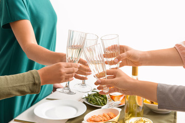 Friends clinking glasses with champagne during dinner, closeup