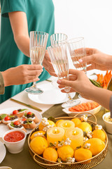 Friends clinking glasses with champagne during dinner, closeup