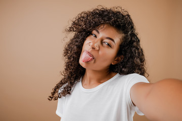 lovely happy black young woman making selfie isolated over brown